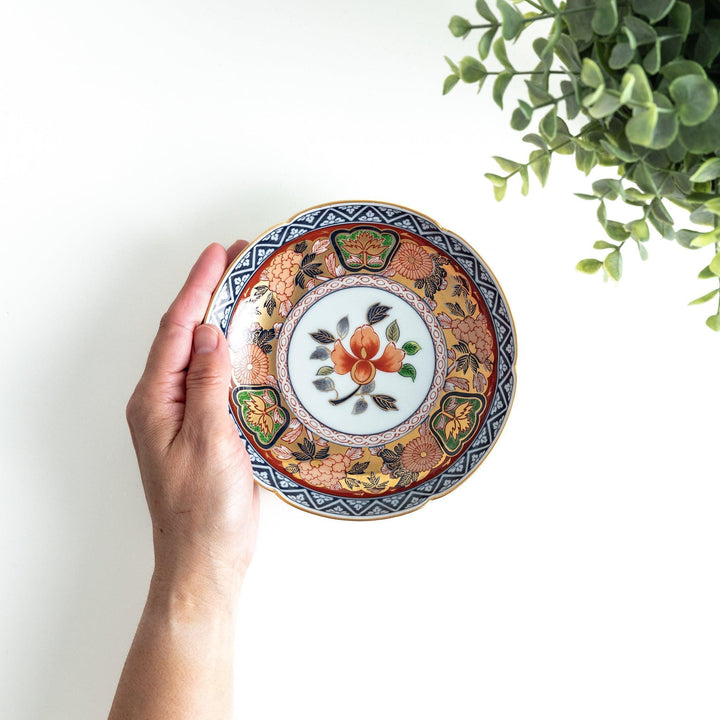 Dessert plate with central floral motif bordered by multicolored patterns and gold blue traditional designs.