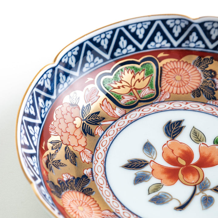 Dessert plate with central floral motif bordered by multicolored patterns and gold blue traditional designs.