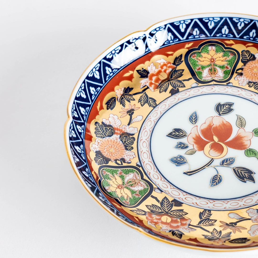 Floral salad plate with gold detailing and red flower center surrounded by green blue and gold patterns.