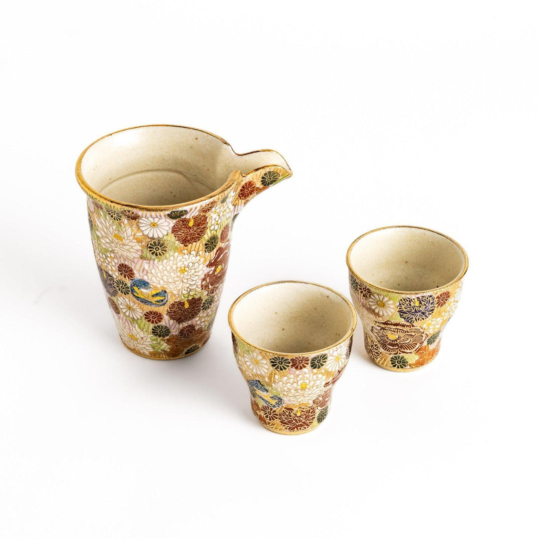 Japanese sake set with gold and pastel floral pattern including pitcher and two matching cups for serving.