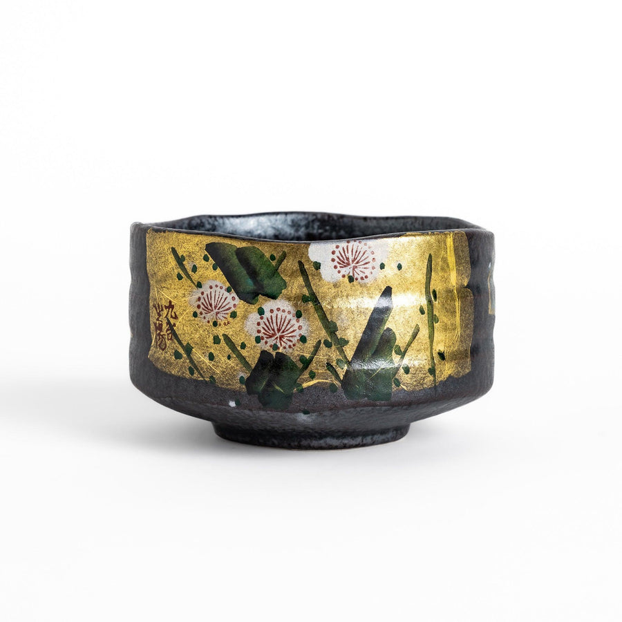 Matcha Bowl featuring a beautiful gold leaf and plum blossom design, set against a dark, textured background.