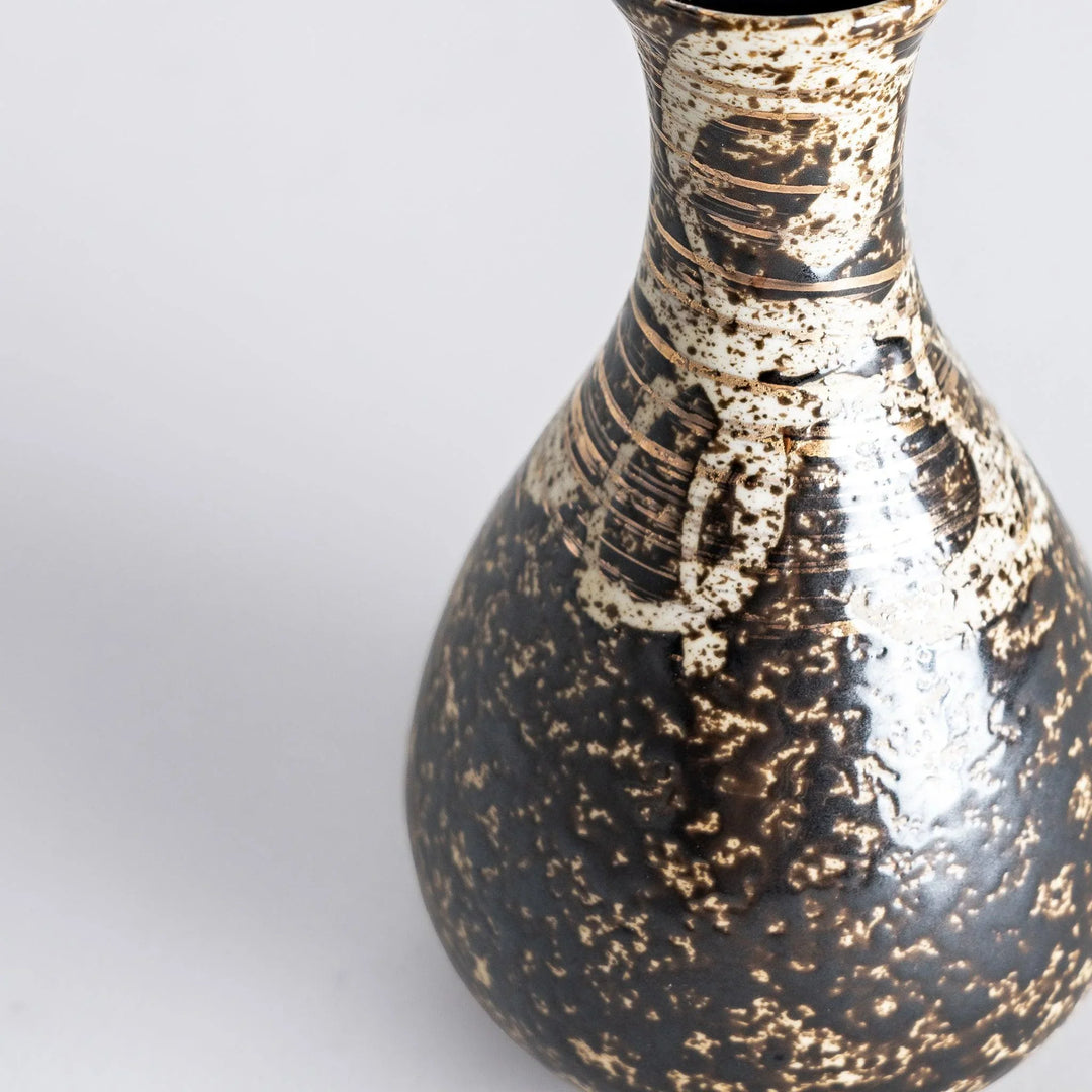 Close-up shot of the sake flask, focusing on the detailed texture and gold accents.