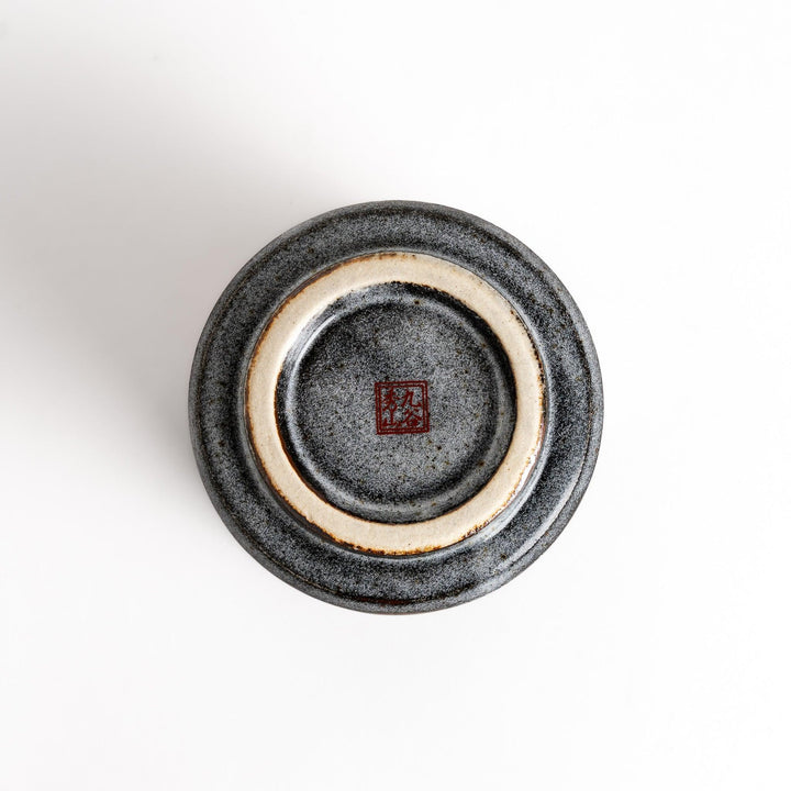 Gray ceramic teacup with gold and pastel floral pattern speckled glaze and flared rim for elegance.