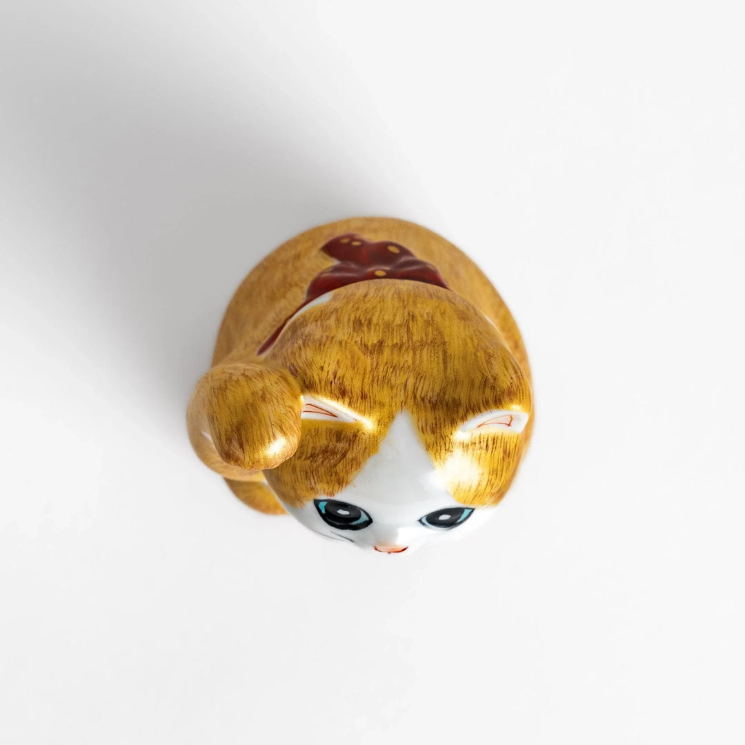 Maneki Neko figurine with a golden brush design, featuring a waving cat with a collar and bell for good luck.
