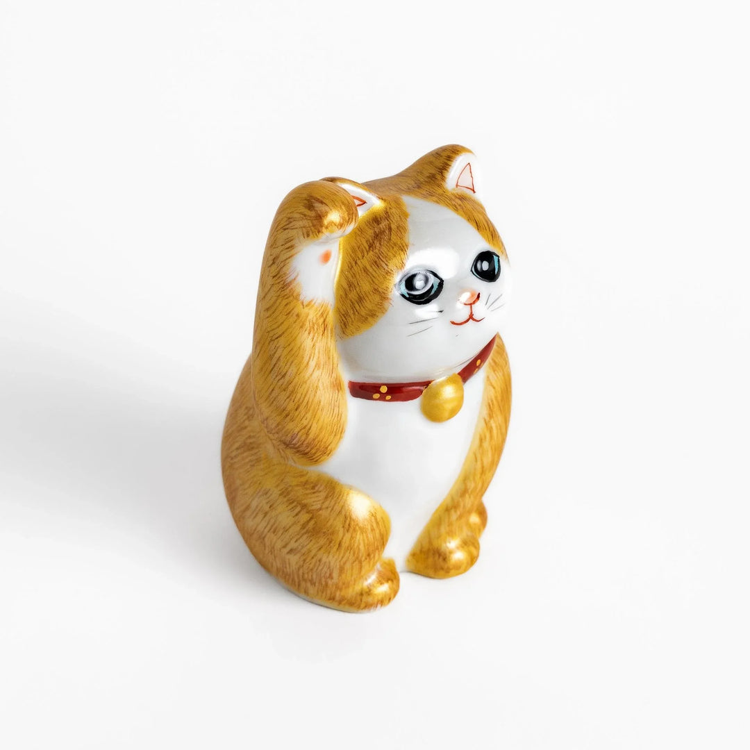 Maneki Neko figurine with a golden brush design, featuring a waving cat with a collar and bell for good luck.