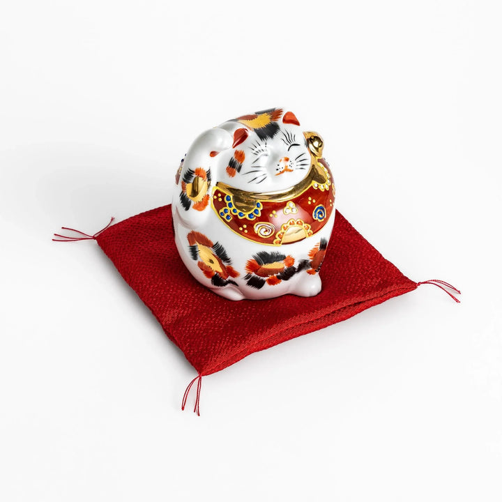 Maneki Neko figurine featuring a golden calico design, a raised paw, and a red patterned collar for good fortune.