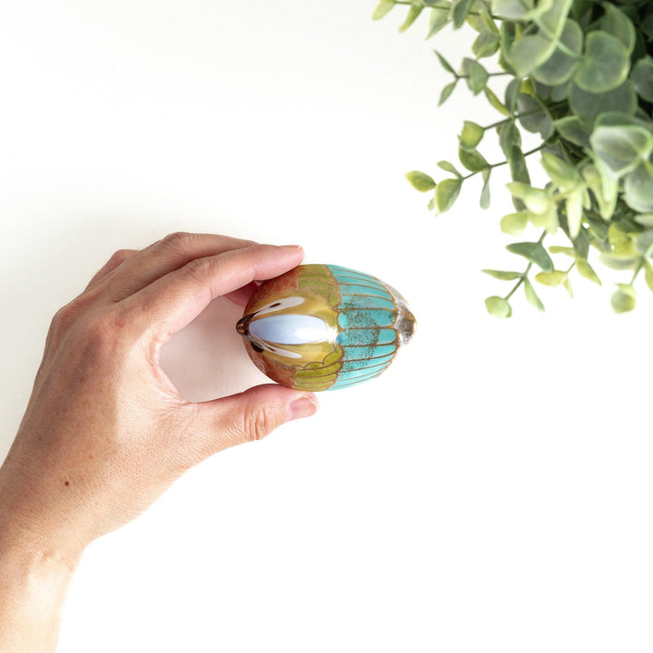 A small condiment bowl shaped like a hen, featuring a detailed painted design with blue, green, and gold accents.