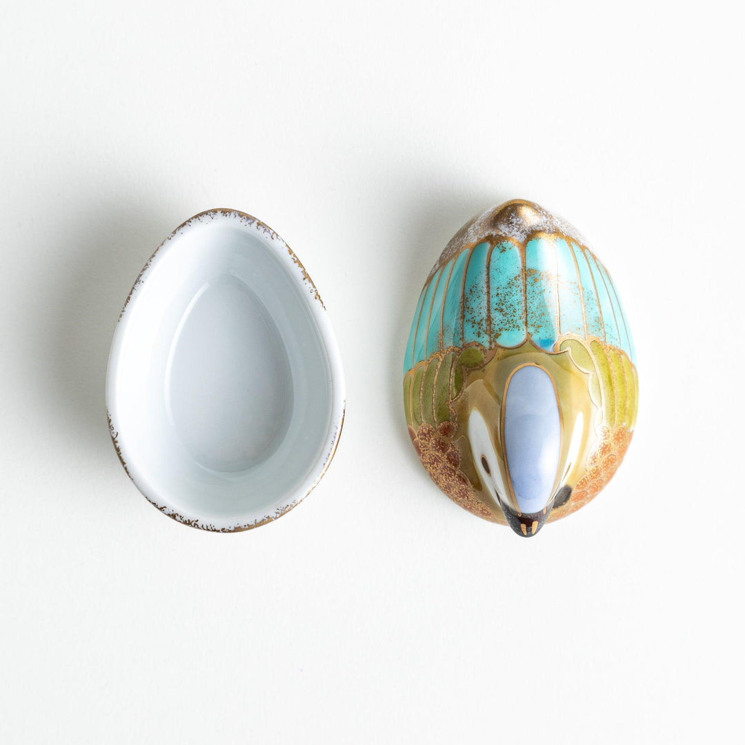 A small condiment bowl shaped like a hen, featuring a detailed painted design with blue, green, and gold accents.