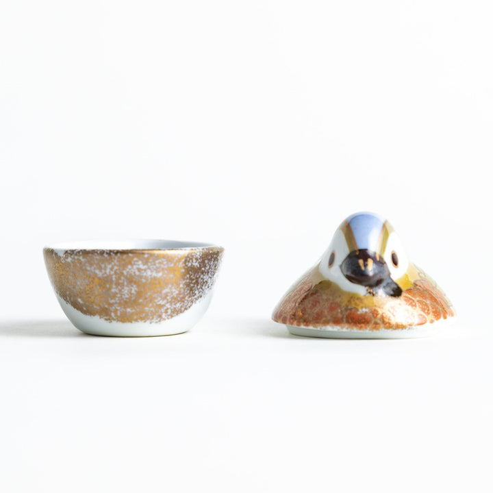 A small condiment bowl shaped like a hen, featuring a detailed painted design with blue, green, and gold accents.