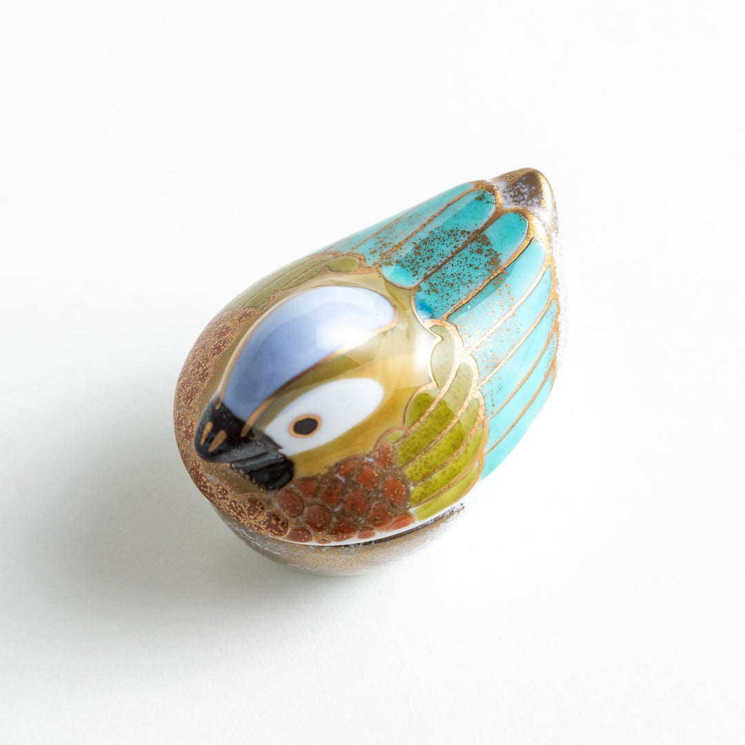 A small condiment bowl shaped like a hen, featuring a detailed painted design with blue, green, and gold accents.