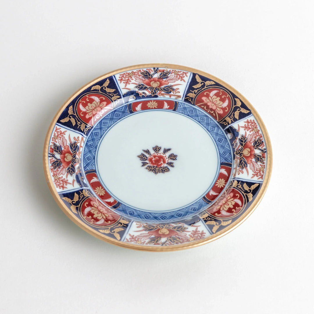 Japanese Imari style porcelain plate with central floral motif and ornate red blue and gold rim pattern.