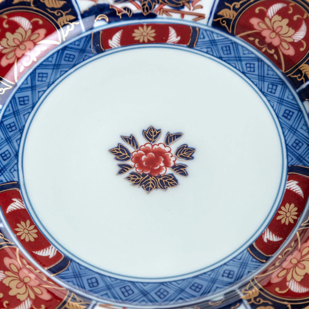 Japanese Imari style porcelain plate with central floral motif and ornate red blue and gold rim pattern.