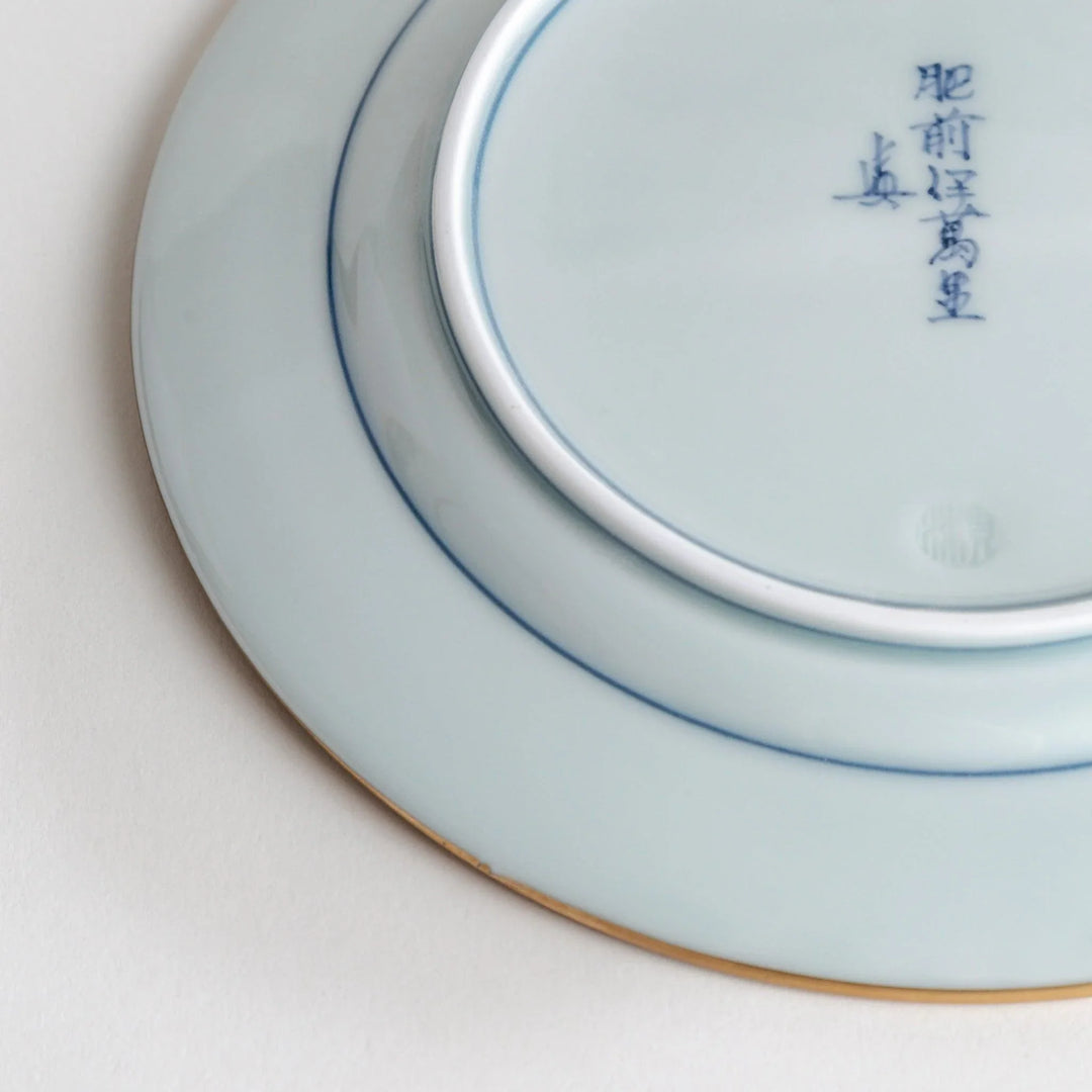 Japanese Imari style porcelain plate with central floral motif and ornate red blue and gold rim pattern.