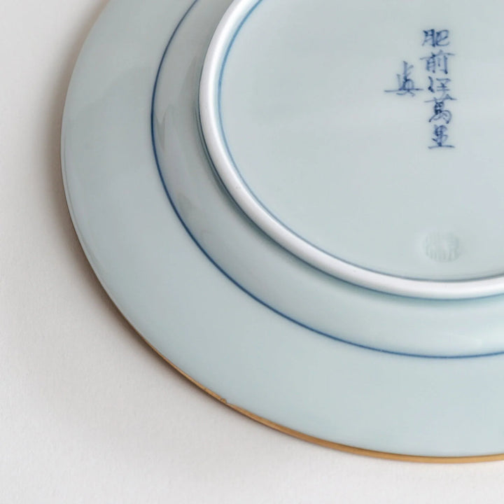 Japanese Imari style porcelain plate with central floral motif and ornate red blue and gold rim pattern.