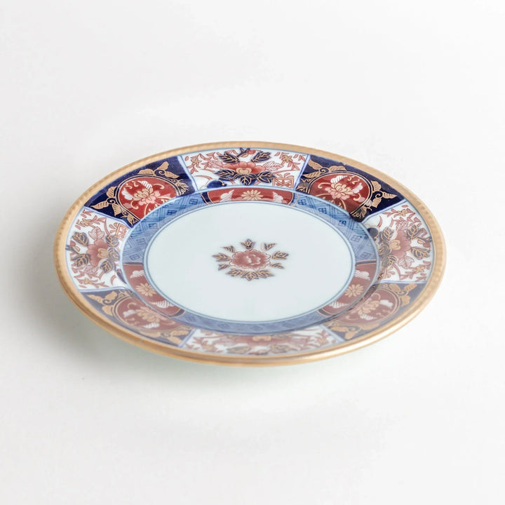 Small Japanese porcelain plate with Imari style floral design and alternating red blue and gold patterns.