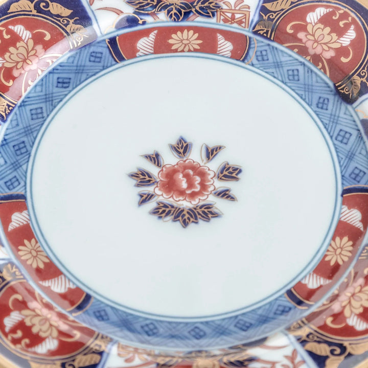 Small Japanese porcelain plate with Imari style floral design and alternating red blue and gold patterns.