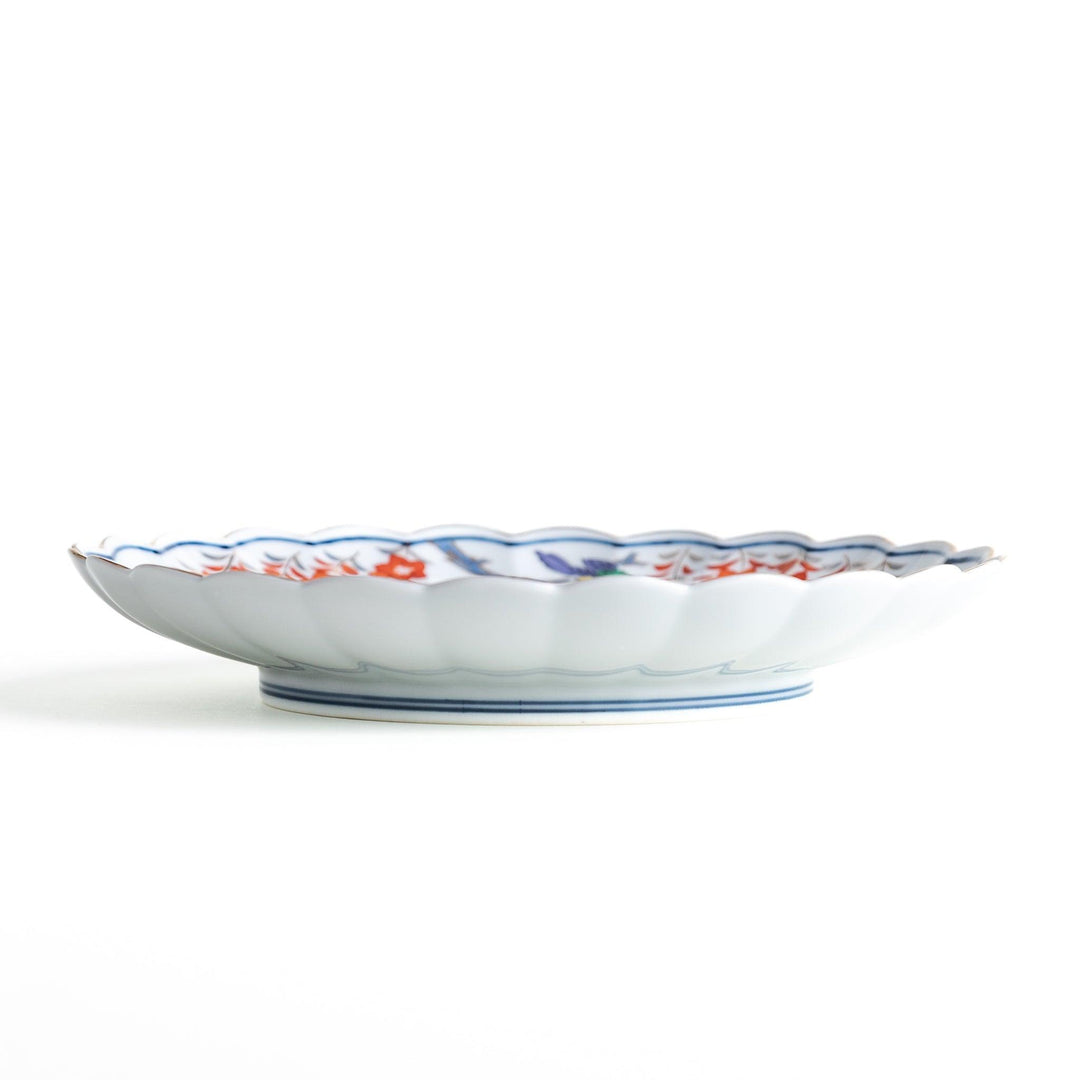 Round scalloped salad plate with floral designs in red yellow and blue and wisteria branch at the top.