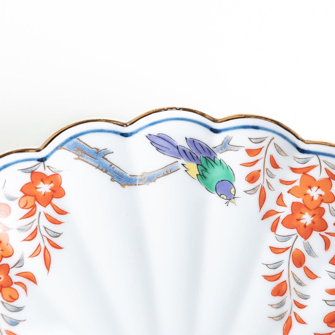 Round scalloped salad plate with floral designs in red yellow and blue and wisteria branch at the top.