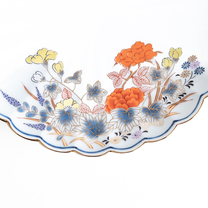 Round scalloped salad plate with floral designs in red yellow and blue and wisteria branch at the top.