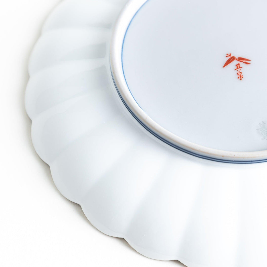 Round scalloped salad plate with floral designs in red yellow and blue and wisteria branch at the top.