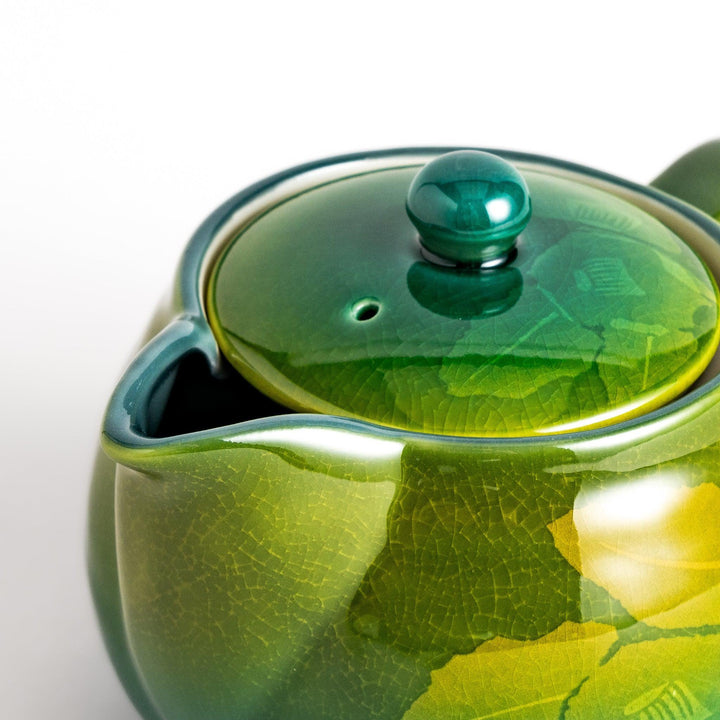 Glossy green ceramic teapot with gradient leaf design and secure lid ideal for everyday tea serving.