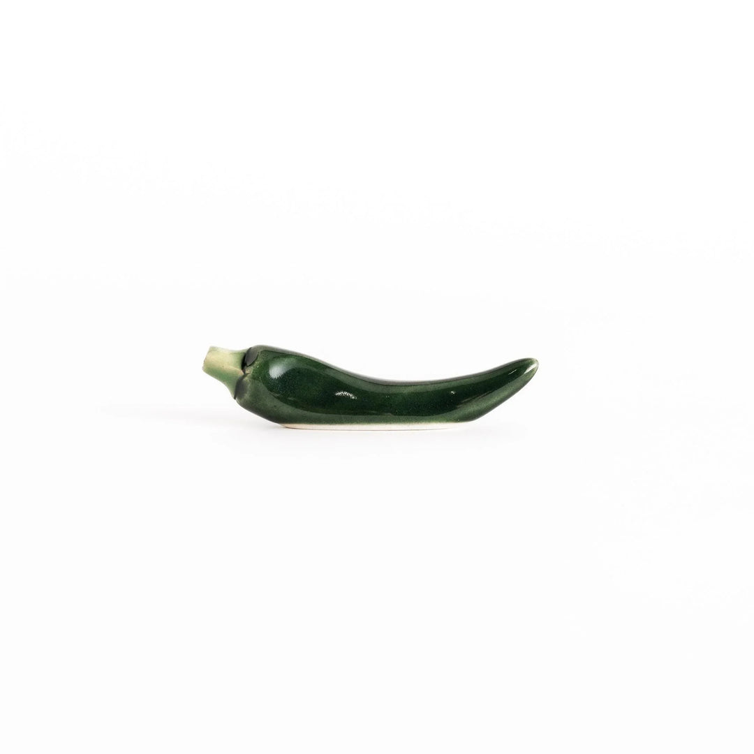 Side view of the green chili pepper chopsticks rest, capturing its curved design and vibrant green color.