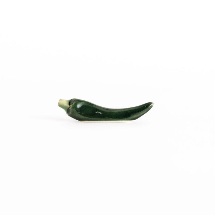 Side view of the green chili pepper chopsticks rest, capturing its curved design and vibrant green color.