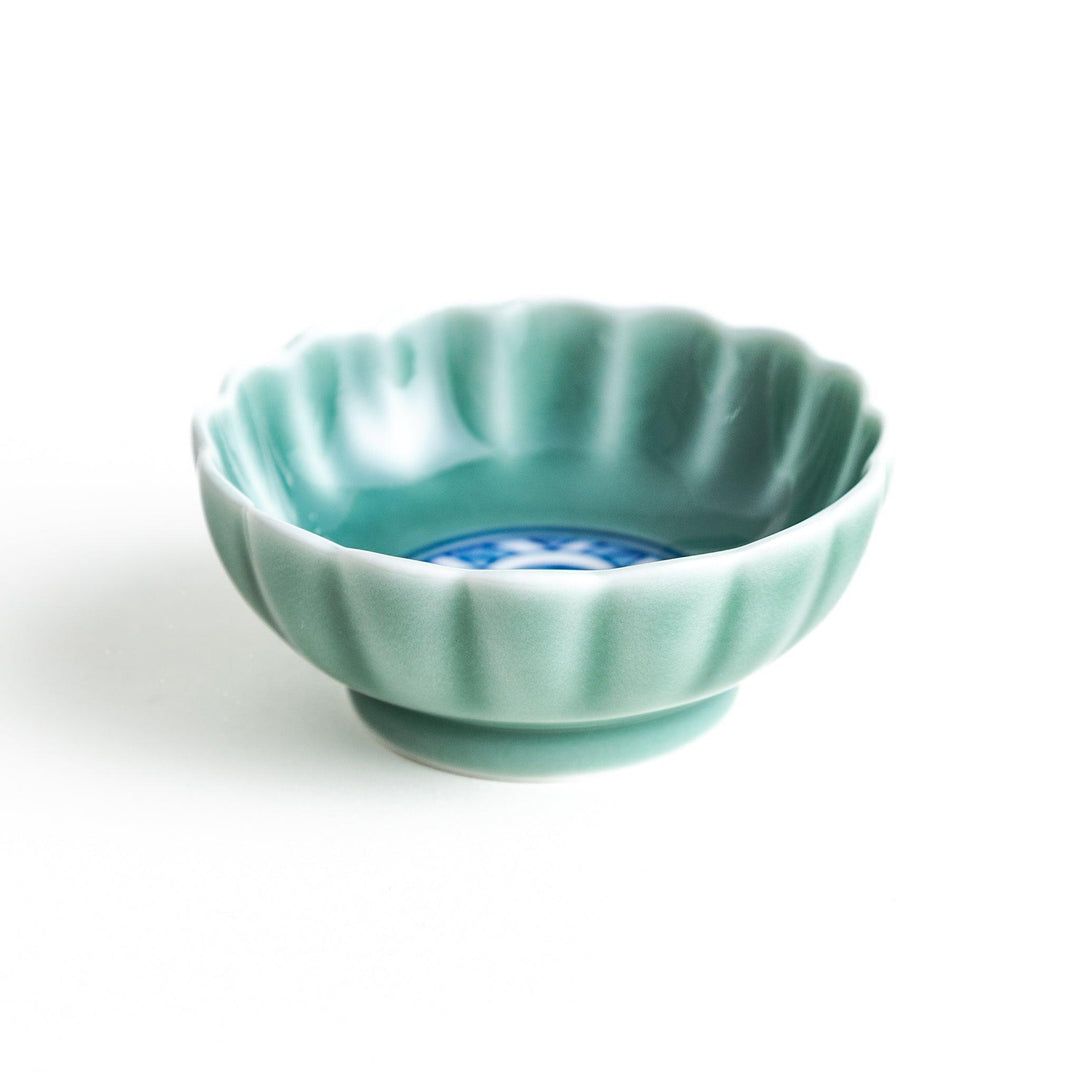 A small green cereal bowl with a scalloped edge and a blue and white wave pattern in the center.