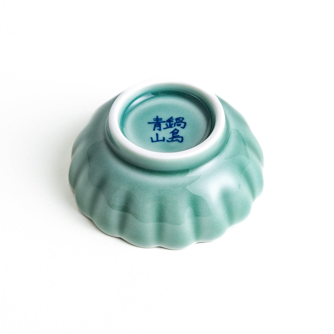 A small green cereal bowl with a scalloped edge and a blue and white wave pattern in the center.
