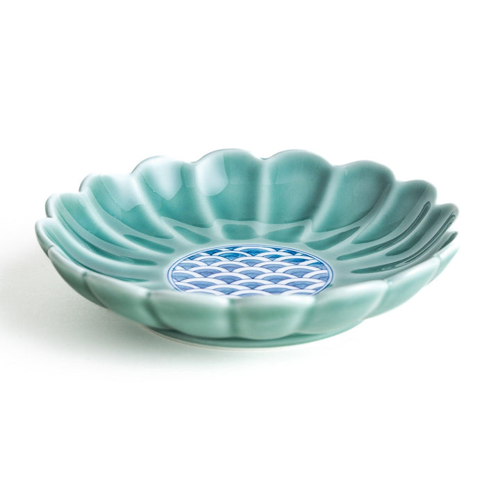 A scalloped-edged green plate with a blue and white wave pattern in the center.