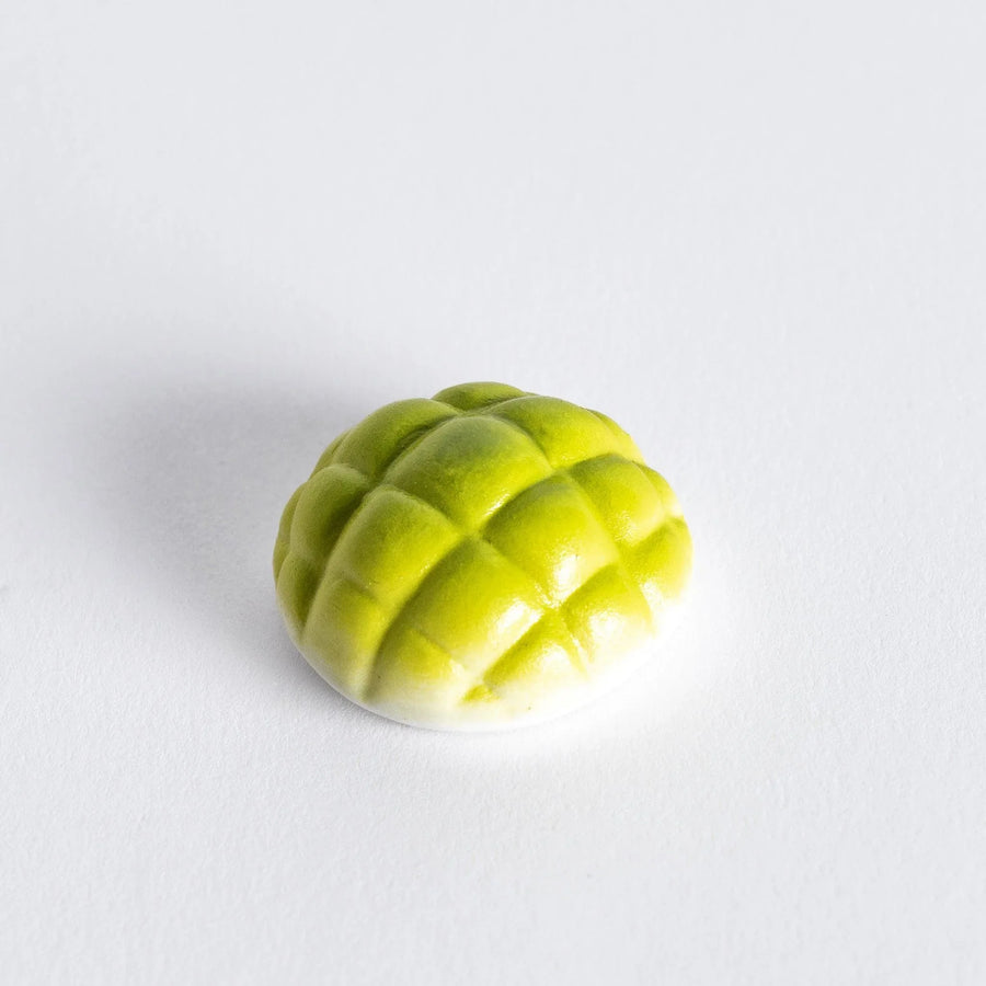Chopstick rest shaped like a green melon pan, featuring intricate details to resemble the texture of the melon bun.