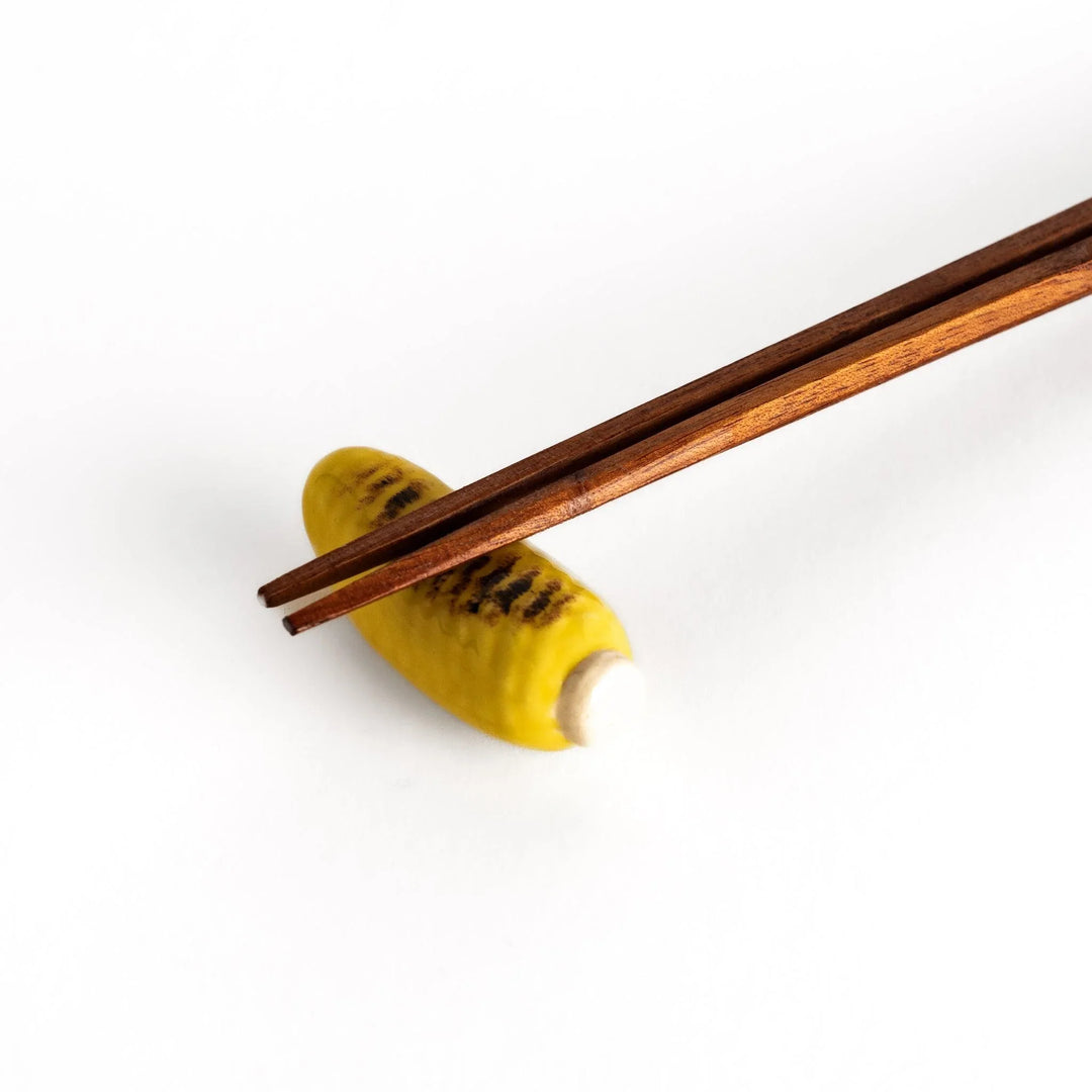 Grilled corn chopstick rest with charred yellow surface and lifelike details adding fun to table setting.