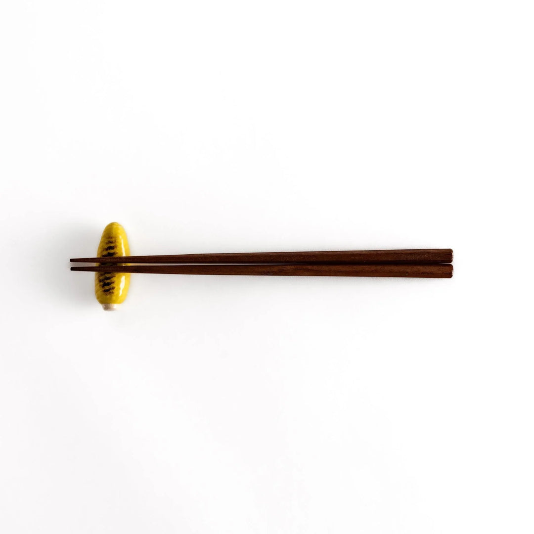 Grilled corn chopstick rest with charred yellow surface and lifelike details adding fun to table setting.