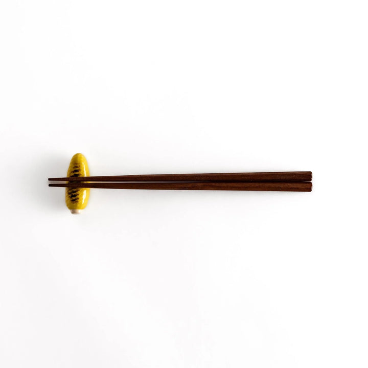 Grilled corn chopstick rest with charred yellow surface and lifelike details adding fun to table setting.