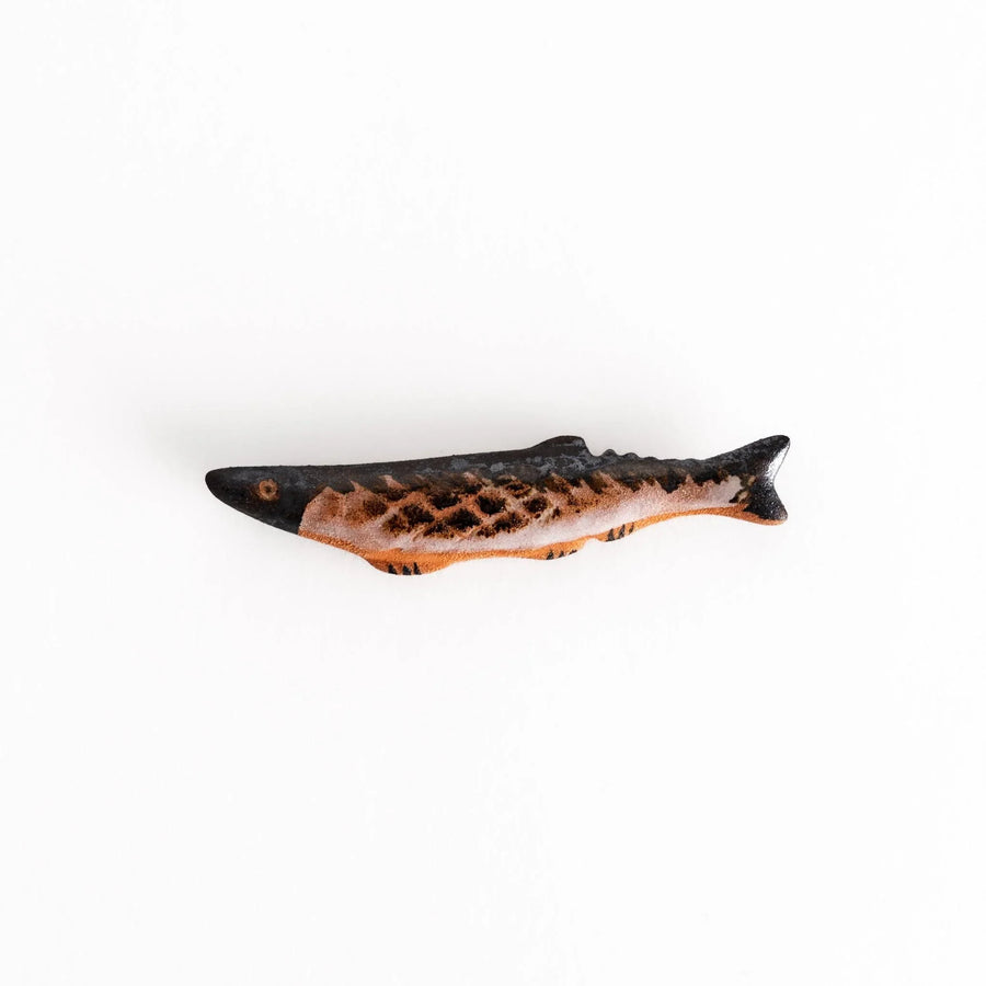 Ceramic chopstick rest shaped like grilled Pacific saury with textured glaze for realistic dining accent.