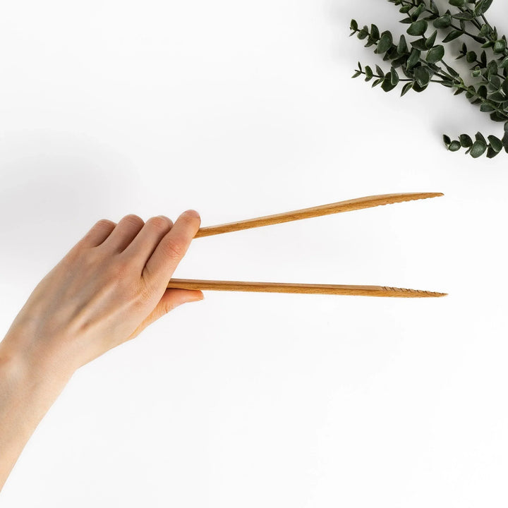 Handcrafted wooden tongs with a smooth surface and angled tips, perfect for stylishly serving or handling food.
