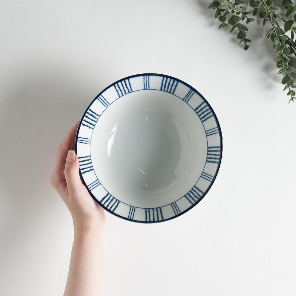 Ceramic ramen bowl with blue striped pattern on white background.