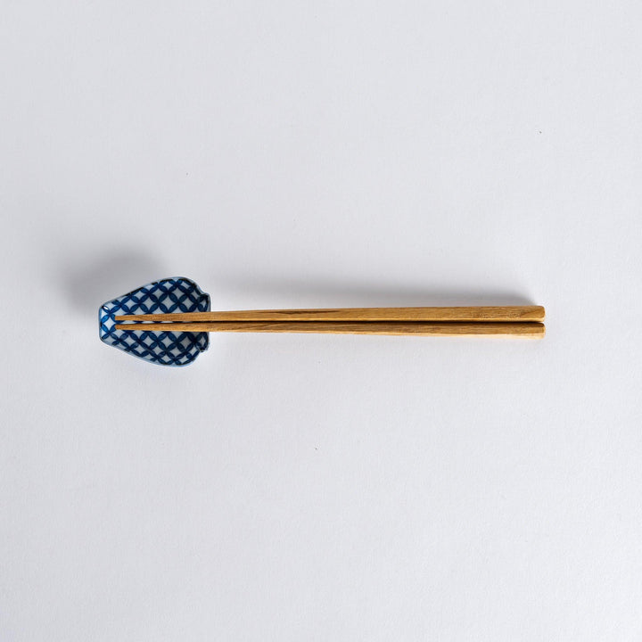Chopsticks placed on the blue geometric vase-shaped sauce dish with a flower pattern, showcasing its unique design.