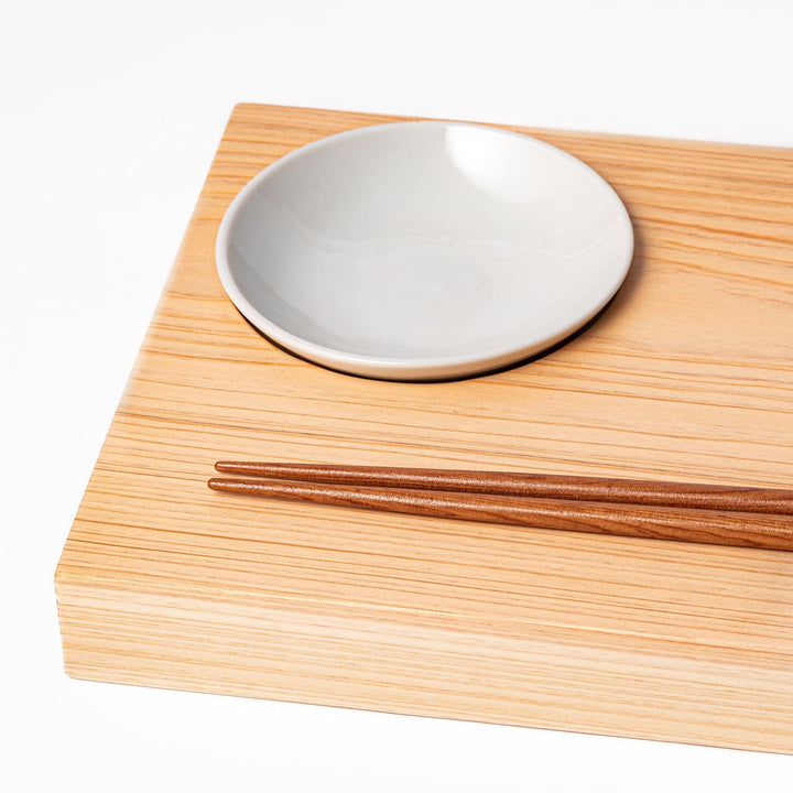 White ceramic dipping dish on hinoki wood sushi plate, showcasing glossy finish and smooth wood grain for sushi service