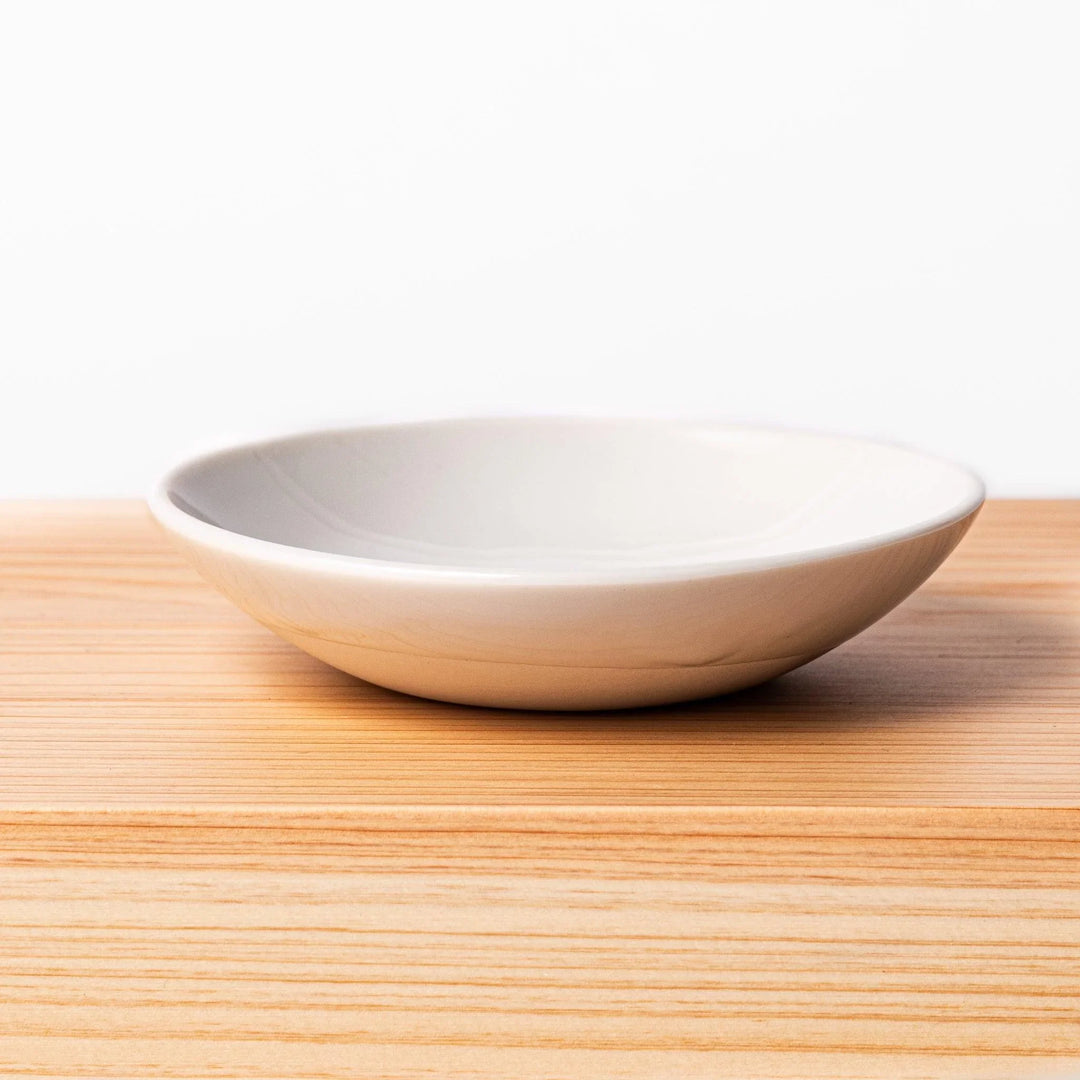 White ceramic dipping dish on hinoki wood sushi plate, showcasing glossy finish and smooth wood grain for sushi service
