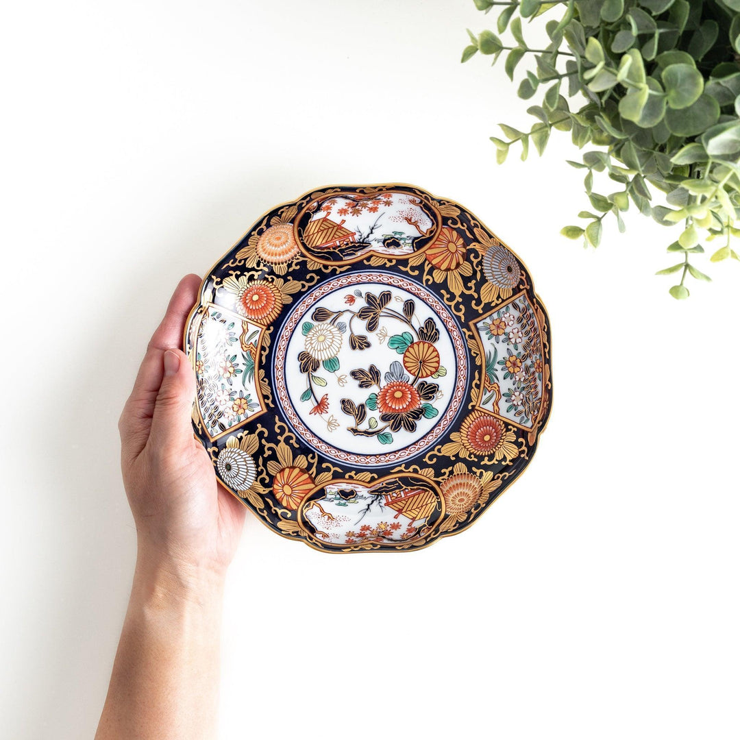 Deep round luncheon plate with dark blue background floral center gold accents and scenic floral border.