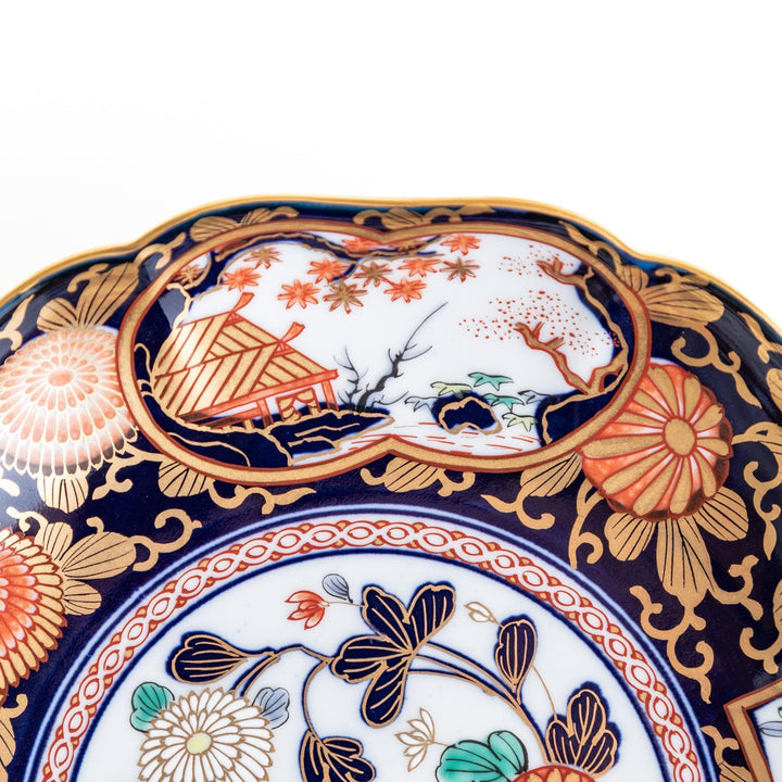 Deep round luncheon plate with dark blue background floral center gold accents and scenic floral border.