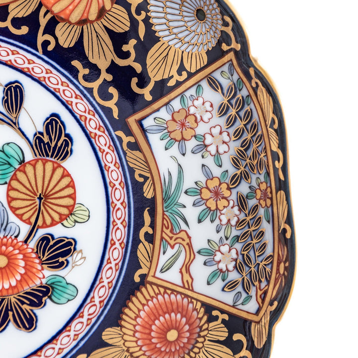 Deep round luncheon plate with dark blue background floral center gold accents and scenic floral border.