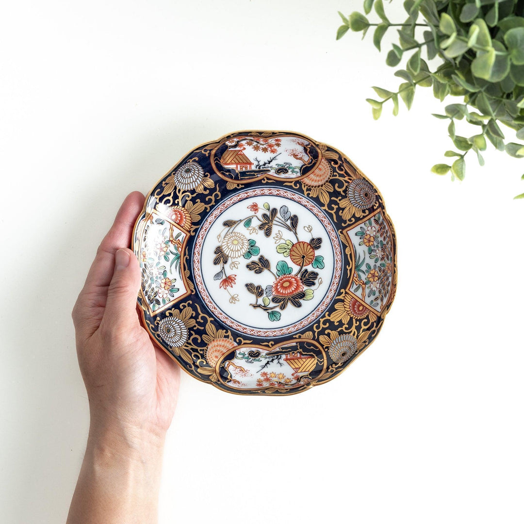 Deep round salad plate with dark blue background floral center and gold red designs of Japanese scenery.