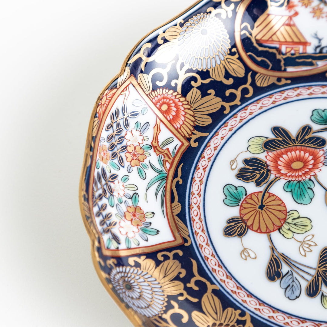 Deep round salad plate with dark blue background floral center and gold red designs of Japanese scenery.