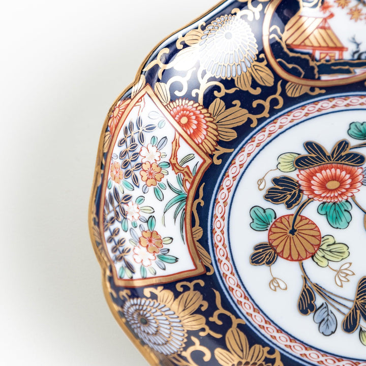 Deep round salad plate with dark blue background floral center and gold red designs of Japanese scenery.