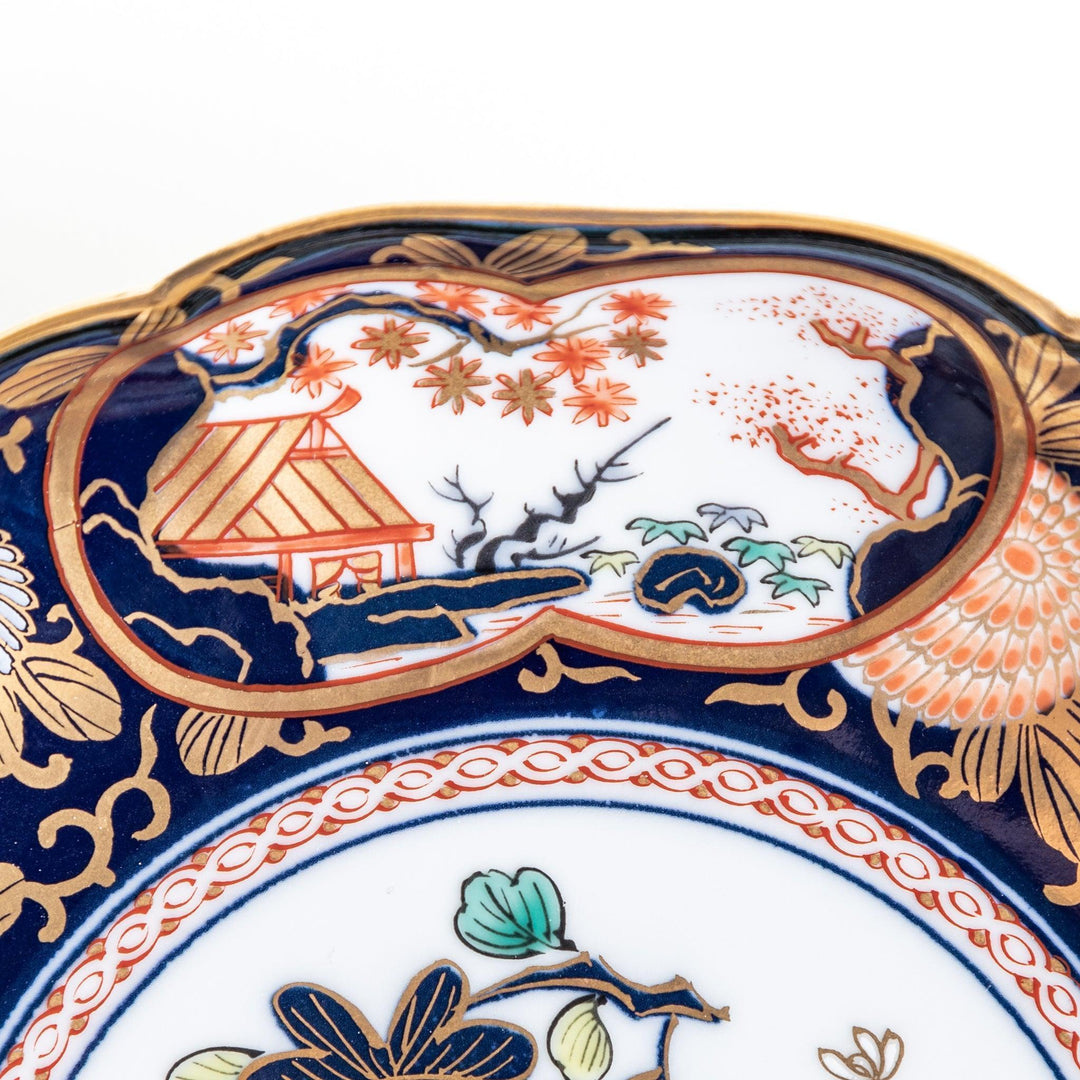 Deep round salad plate with dark blue background floral center and gold red designs of Japanese scenery.