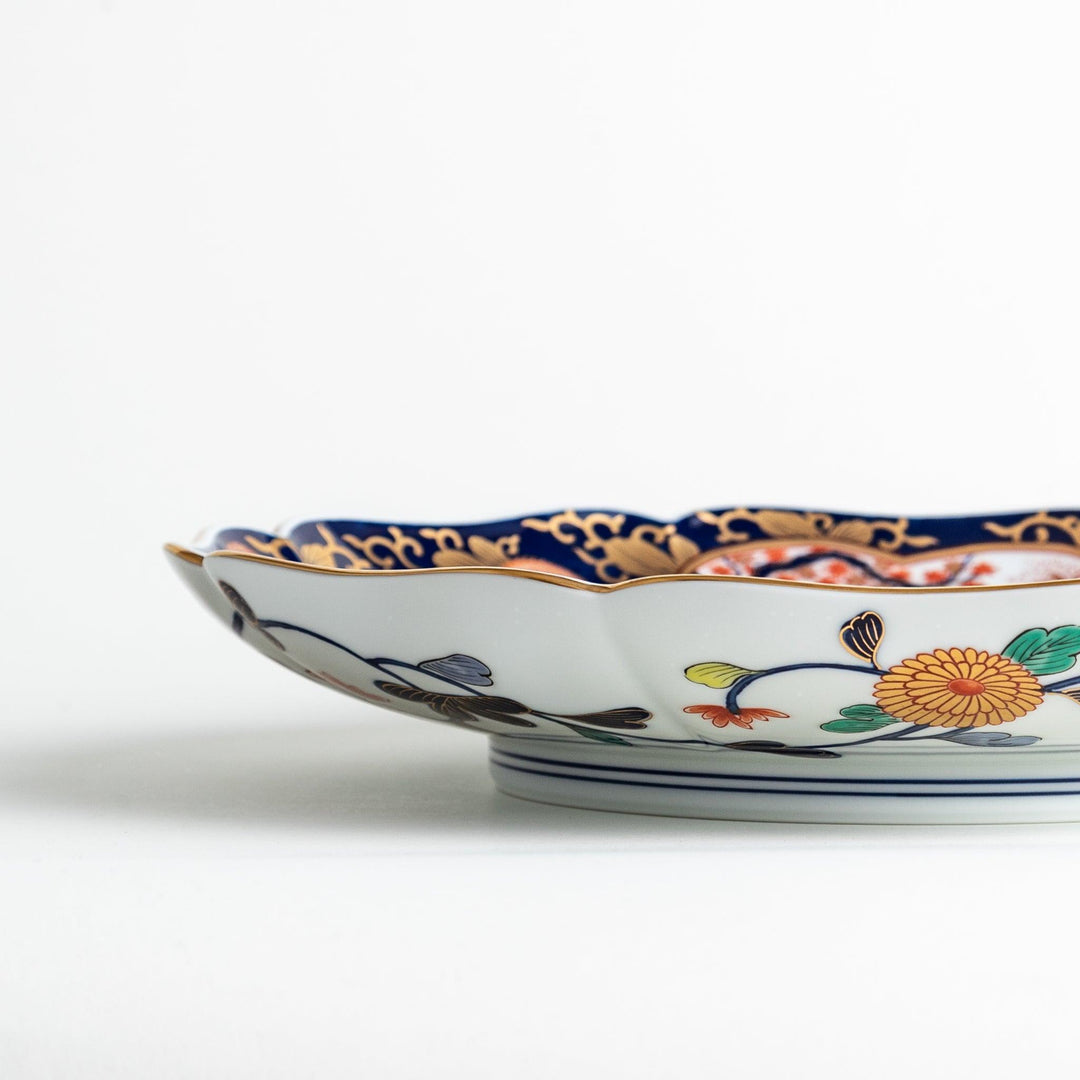 Japanese porcelain serving plate with chrysanthemum and peony motifs in vivid colors and gold detailing on a deep navy base