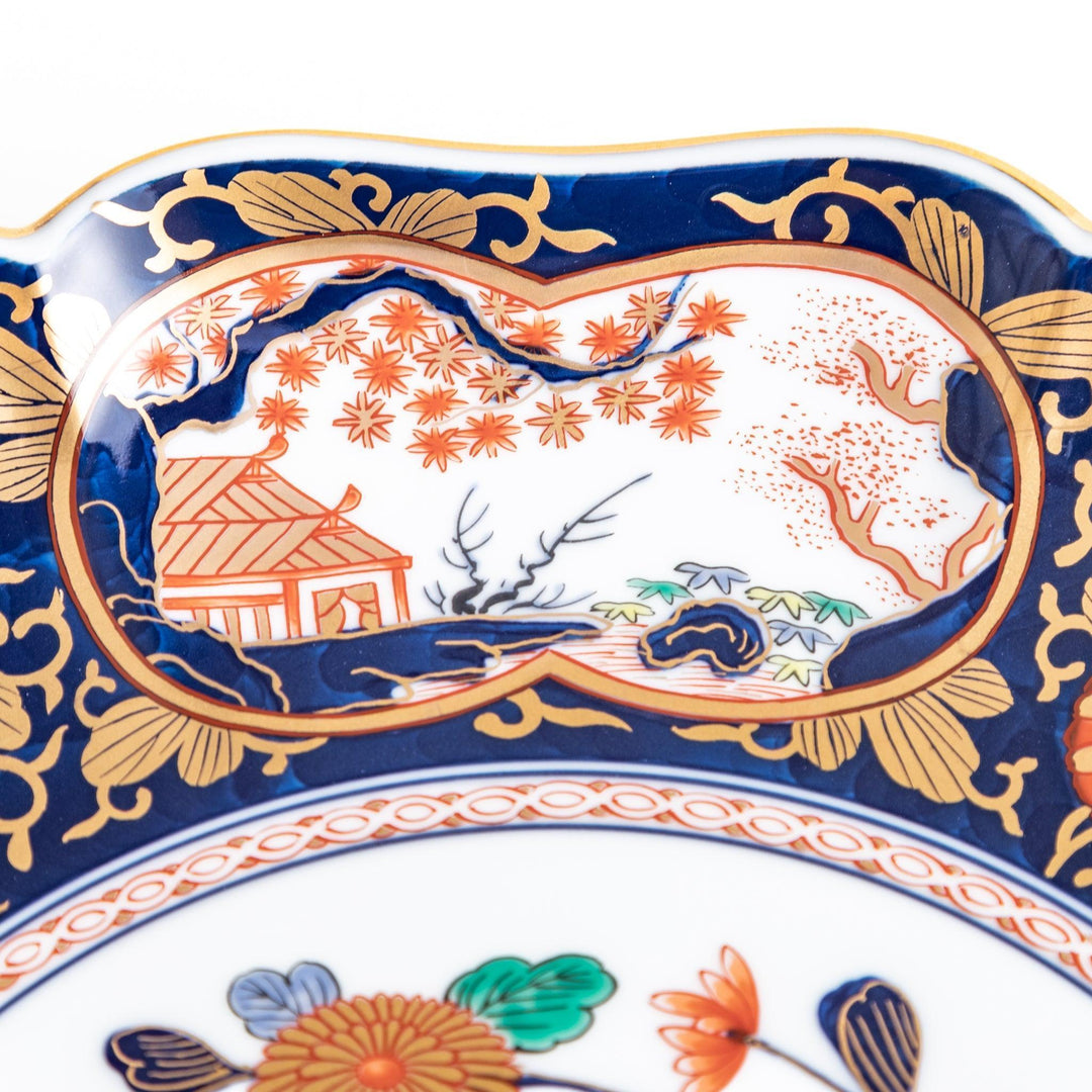 Japanese porcelain serving plate with chrysanthemum and peony motifs in vivid colors and gold detailing on a deep navy base