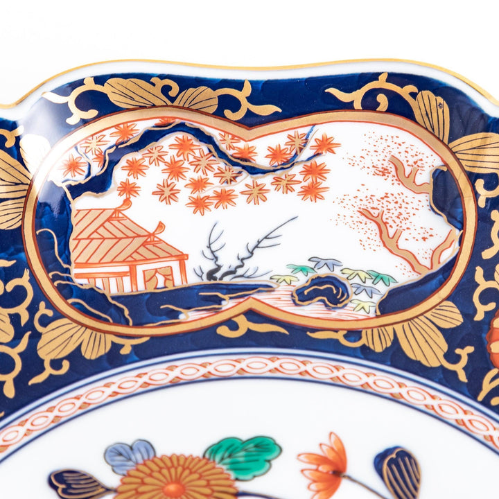 Japanese porcelain serving plate with chrysanthemum and peony motifs in vivid colors and gold detailing on a deep navy base